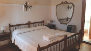 A neatly made bed with a folded towel, a bedside lamp, a nightstand, a mirror, and a wall-mounted light fixture. - Brigitte, centre, 5 minutes walk to the beach, 10 minutes walk trainstation. (Tropea)