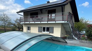 Een huis met een zwembad, een overdekt terras en een balkon.