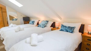 A hotel room with two beds, each with white linens and blue patterned pillows, a wooden nightstand with a lamp, and a large mirror on the wall. - The Cotswold Manor Byre, Exclusive Hot Tub, Games Barn, 70 acres of Parkland (Bampton)