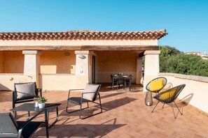 A patio with outdoor furniture, a table, and a chair.