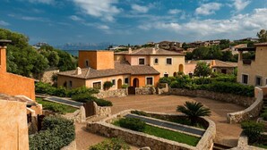 A courtyard with stone walls, a central open space, and buildings with terracotta roofs. - Villaggio Perlacea - PERLACEA 34 (Golfo Aranci)