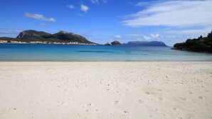 A beach with clear blue water, sandy shore, and distant mountains. - Villaggio Perlacea - PERLACEA 34 (Golfo Aranci)