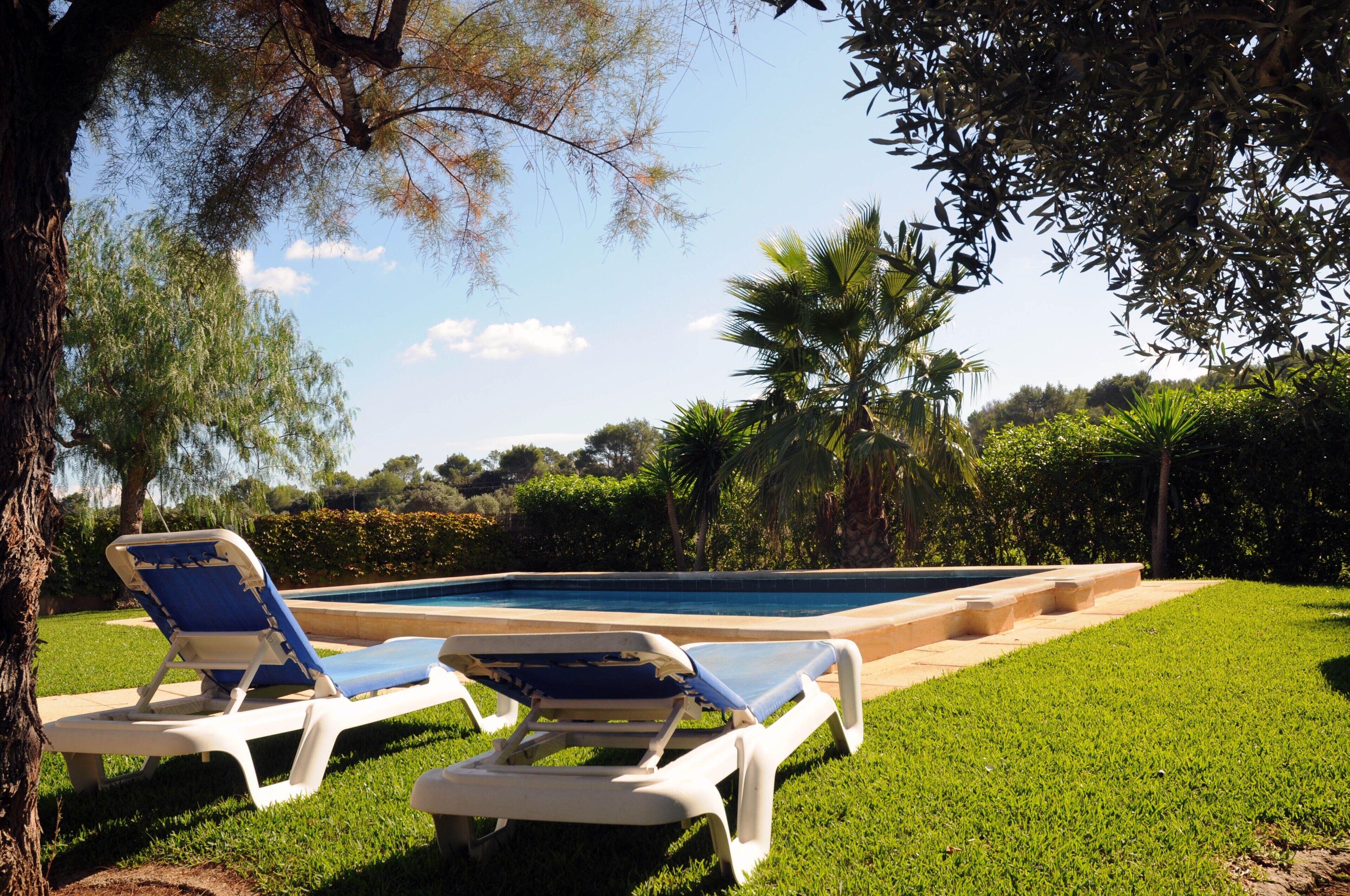 A poolside area with two lounge chairs and a swimming pool.