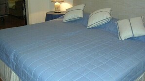 Ein Bett mit einer blauen Decke, vier Kissen und einer Nachttischlampe.