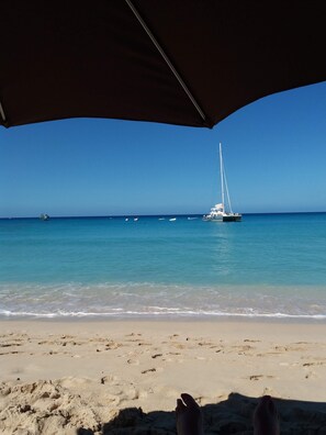 Ein Strand mit Segelboot im Wasser, blauem Himmel und sandigem Ufer.