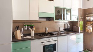 A kitchen with white cabinets, a gas stove, a sink, and a window above the counter.
