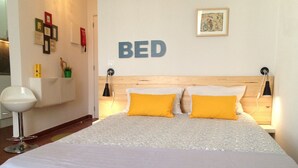 Une chambre à coucher avec un grand lit, deux lampes de chevet, une œuvre d’art accrochée au mur et un panneau indiquant « LIT ».