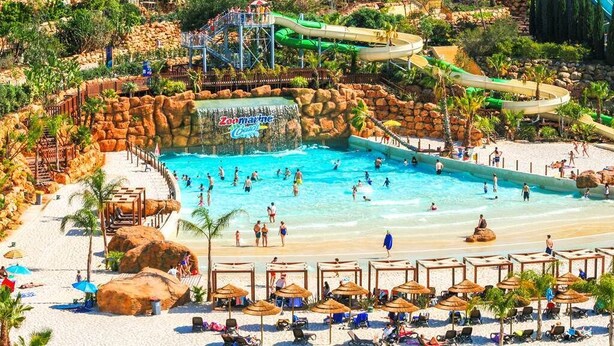Un espace piscine équipé d’un toboggan, de chaises longues et de parasols.