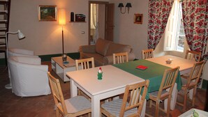 Una habitación acogedora con una mesa de comedor, sillas, un sofá, una lámpara y una ventana con cortinas florales.