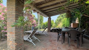 Un patio al aire libre con pilares de ladrillo, una pérgola y arreglos de asientos.
