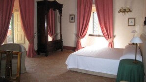 Un dormitorio con cama, armario de madera, espejo y ventana con cortinas.