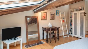 A cozy attic bedroom with a skylight, a TV, a mirror, a desk, a ladder, and a wardrobe. - Gabry's Rooftop Terrace Home with  breathtaking Views of Lucca & Tuscany (Lucca)