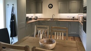 Une cuisine moderne avec des meubles de couleur grise, une table à manger en bois et un saladier en bois.