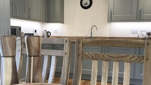 Une cuisine avec des chaises en bois, une table en bois et des armoires vert clair.