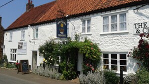 A traditional white building with a red-tiled roof, a sign reading "The Rose & Crown Freehouse," and a small garden with various plants and flowers. - Amber Cottage 3 Bed , In Snettisham, North Norfolk  dogs welcome (Snettisham)