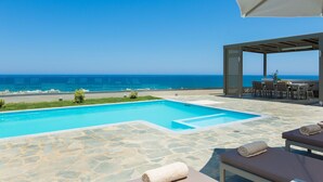 A pool with a view of the sea, outdoor seating, and a covered area with tables and chairs. - Villa Naya, walking distance to beach & sea view! (Rethymno)