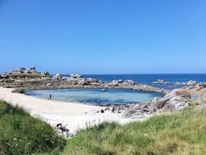 A rocky beach with clear water and a sandy area. - A beachfront cottage (Cléder)