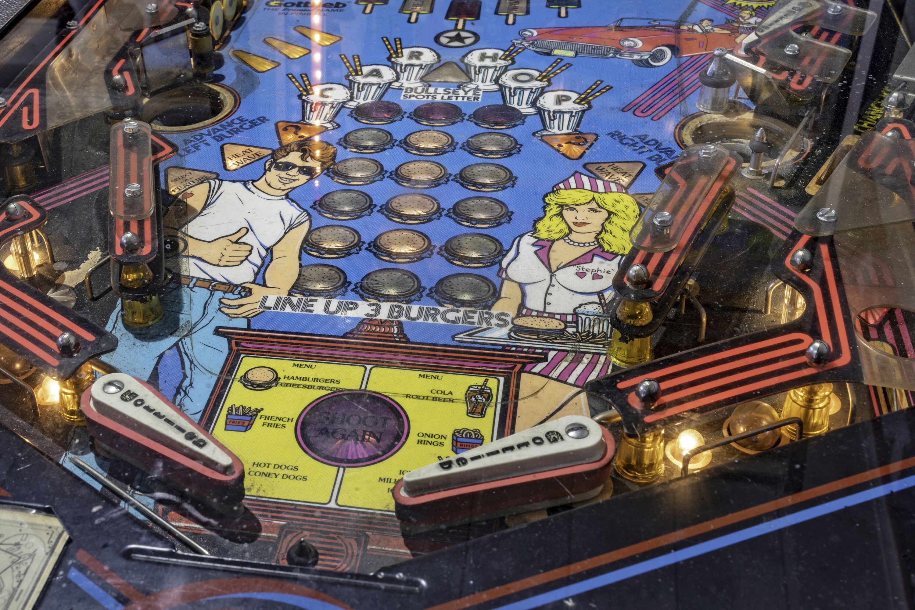 Un flipper doté d’un plateau de jeu coloré, sur lequel figurent des personnages et du texte liés aux hamburgers et aux frites.
