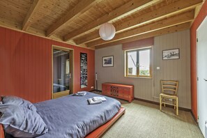 A bedroom with a bed, a dresser, a chair, and a window. - A beachfront cottage (Cléder)