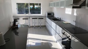 Eine moderne Küche mit großem Fenster, Edelstahlgeräten und drei Barhocker.