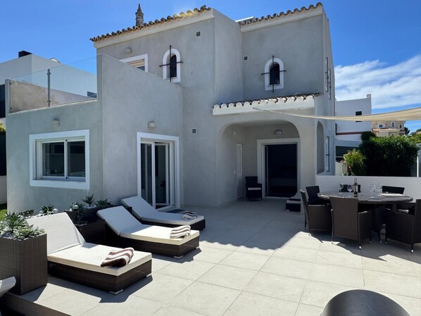 A modern building with a patio area featuring outdoor furniture and a dining setup.