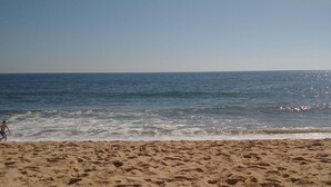 Ein sandiger Strand mit Fußspuren, die zum Wasser führen.