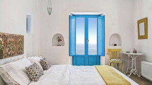 Une chambre à coucher avec un lit, une porte bleue, une petite table et une chaise.