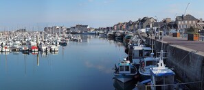 Un port de plaisance où de nombreux bateaux sont amarrés le long de la rive, entouré de bâtiments et sous un ciel dégagé.