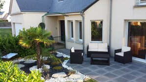 Een modern huis met een patio, straatmeubilair en een kleine tuin met een palmboom.