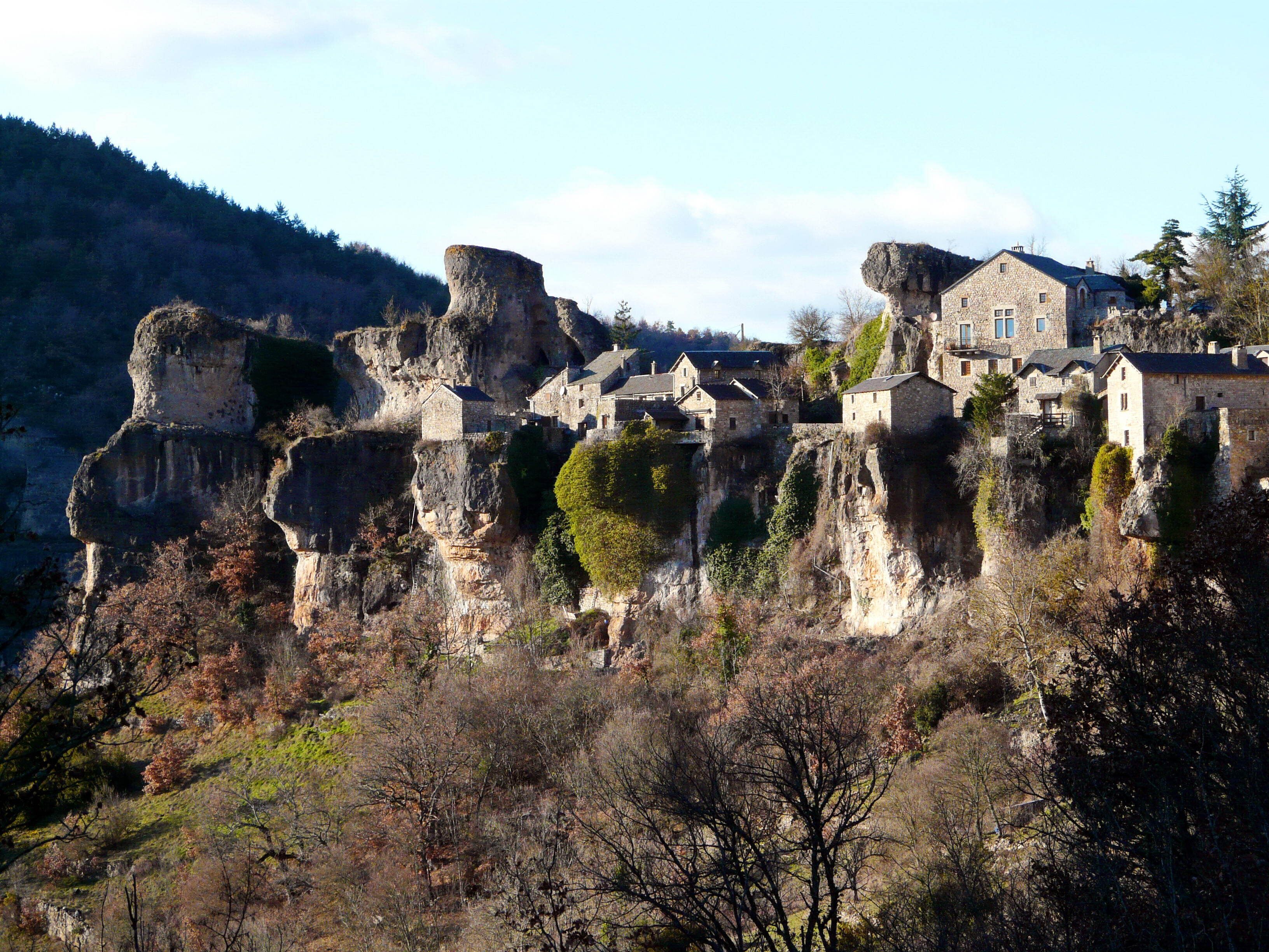 Un bâtiment en pierre, doté de nombreuses pièces, qui est construit sur une falaise.
