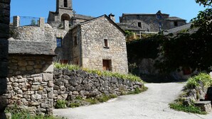 Un edificio de piedra con una pequeña torre de campanas, un sendero de tierra que lo lleva a ella y muros de piedra circundantes.