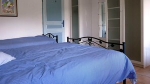 Un dormitorio con dos camas, un armario y una puerta con espejo.