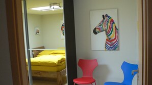 Una habitación con una cama, dos sillas y un cuadro de una cebra en la pared.