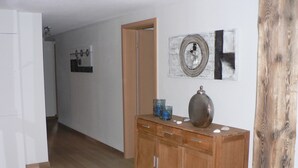 Un pasillo con suelo de madera, un mueble de madera con cajones y un espejo en la pared.