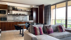 Ein modernes Wohnzimmer mit einer Couch, einem Esstisch und Küchengeräten.