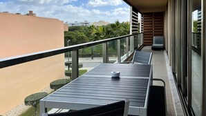 Ein Balkon mit Tisch, Stühlen, Geländer und Blick auf den Himmel und die Häuser.