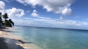 A beach with clear turquoise water, a sandy shore, and palm trees. - Charming 2 bedroom 2 shower room self catering  apt on a gorgeous quiet beach (Fitts Village)