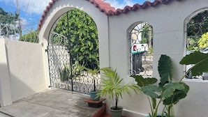 A white building with arched doorways and windows, potted plants, and a concrete patio. - Charming 2 bedroom 2 shower room self catering  apt on a gorgeous quiet beach (Fitts Village)