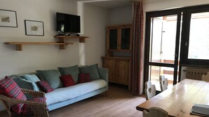 En hyggelig stue med sofa, spisebord, fjernsyn og skab.