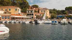 Uma marina com barcos atracados, rodeada por edifícios com arquitetura mediterrânea.