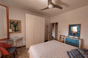 A bedroom with a bed, a dresser, a chair, a desk, a wardrobe, and a ceiling fan. - Villa Giolù: La Terrazza Apartment, near the beach ! (Portoferraio)