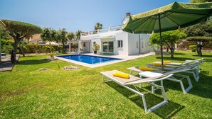 Una casa moderna con piscina, mobiliario exterior y un césped bien cuidado.