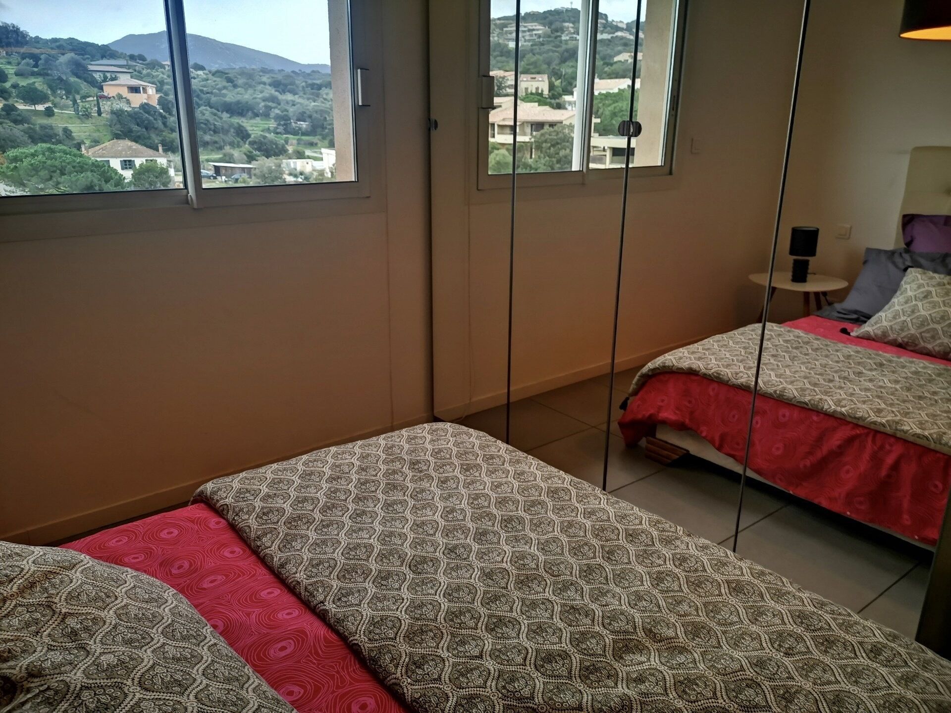 Ein Schlafzimmer mit zwei Betten, einem kleinen Tisch und einem Spiegel.