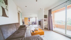 En moderne stue med sofa, sofabord og pejs. I baggrunden er der et spiseområde med bord og stole.
