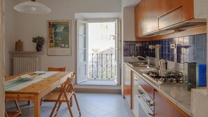 A kitchen with a dining table, chairs, a stove, and a window with a view. - Lakefront apartment with garden in the center of Orta San Giulio (Orta San Giulio)