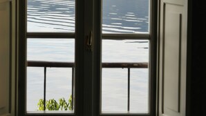 A room with two windows overlooking a body of water and a hilly landscape. - Lakefront apartment with garden in the center of Orta San Giulio (Orta San Giulio)