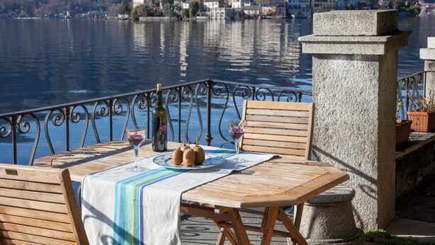 A table with a white tablecloth, two wine glasses, and a bottle of wine. - Lakefront apartment with garden in the center of Orta San Giulio (Orta San Giulio)