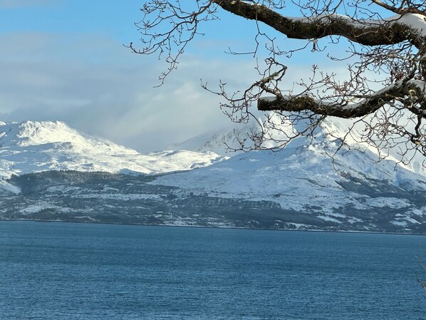Paisatge de muntanya amb cims nevats i un cos d'aigua al primer pla.