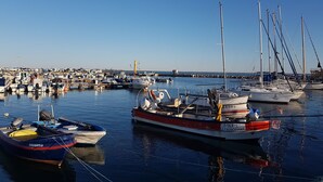 Ein Yachthafen mit verschiedenen Schiffen, ruhigem Wasser und blauem Himmel.