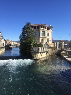 Ein historisches Gebäude mit großem Fenster und Balkon, an einem Fluss gelegen.